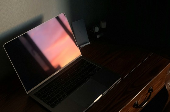A laptop screen reflects sunlight, making the content on the screen difficult to see
