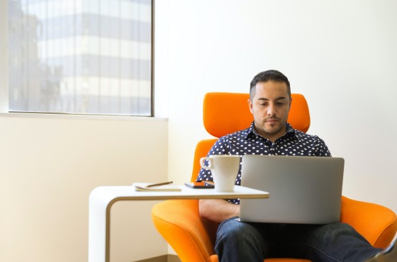 Man in oranje stoel met laptop